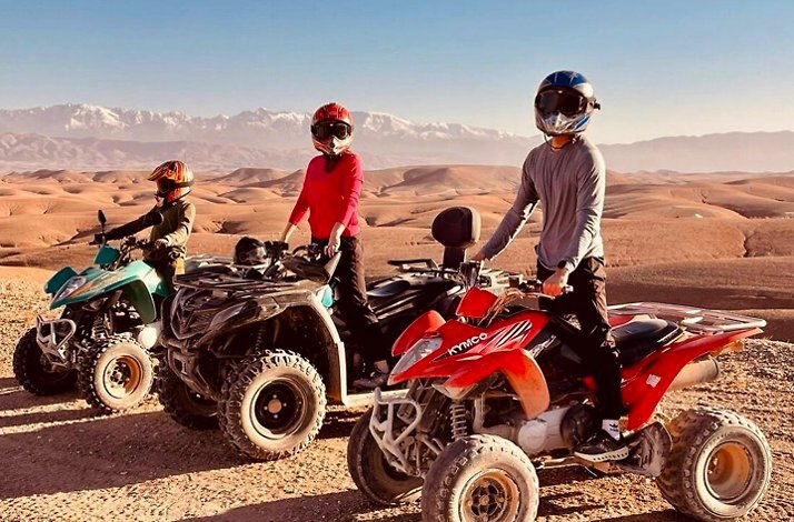 Three people riding quad bikes across rocky trails.