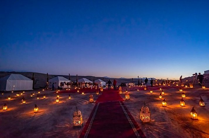 A nighttime scene at Agafay Desert featuring  red carpets and candles