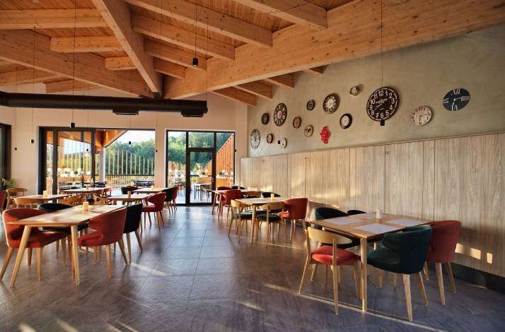 The interior of Plitvice Restaurant, featuring the dining area, large windows, and various clocks design. 