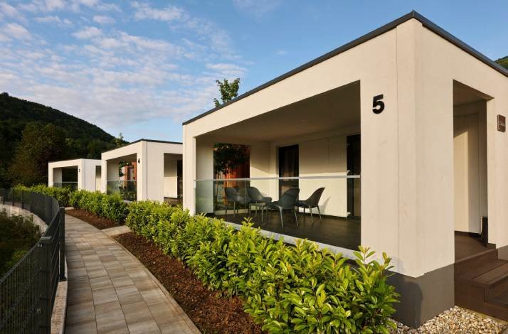 Modern, minimalist cottages surrounded by greenery with private terraces at Camping Plitvice.