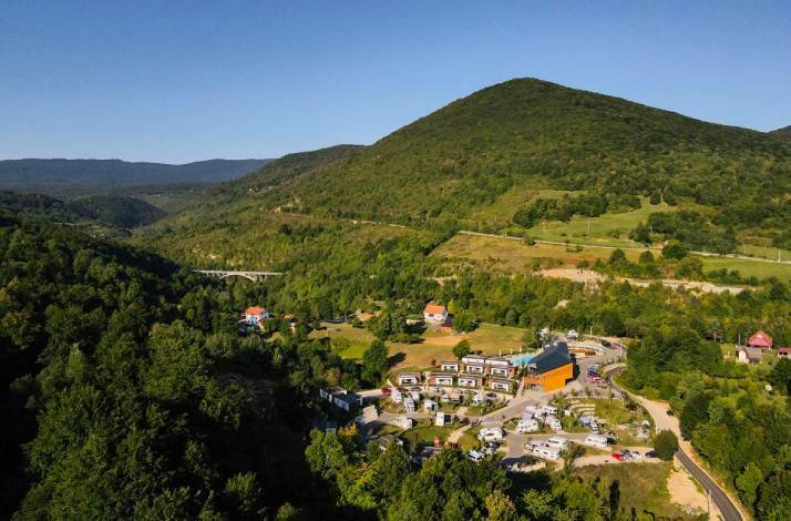 Aerial view of a lush mountain landscape with scattered buildings nestled among the greenery.