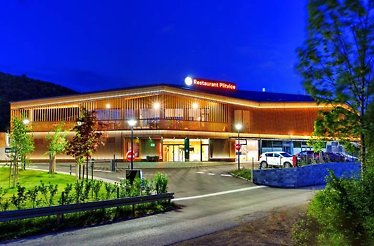 The exterior of Plitvice Restaurant, captured at twilight, highlighting its wooden design and modern ambiance.
