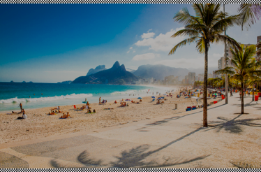 Sunbathers and palm trees line a vibrant sandy beach with mountains in the background.