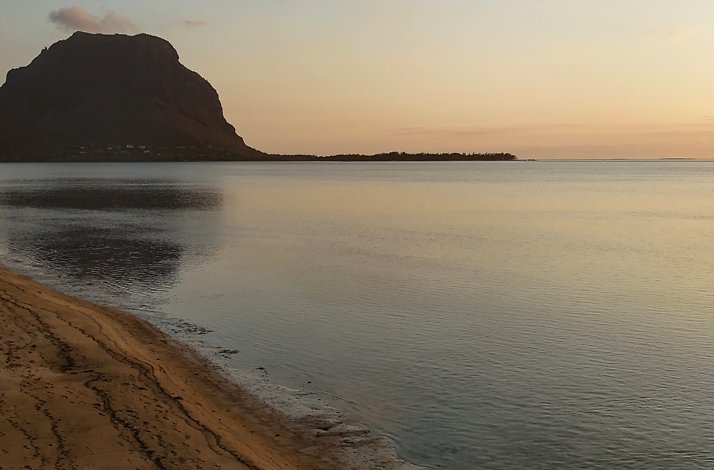 A serene morning on a beach overlooking Le Morne Brabant mountain, Mauritius.