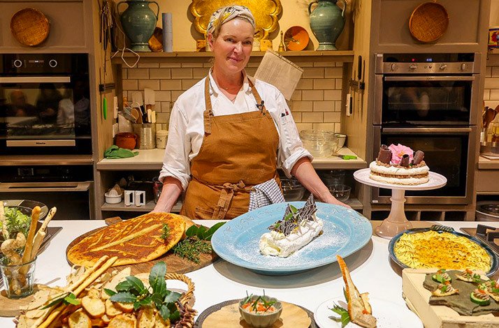 Celebrity chef Rachel Allen standing behind a table spread with food.