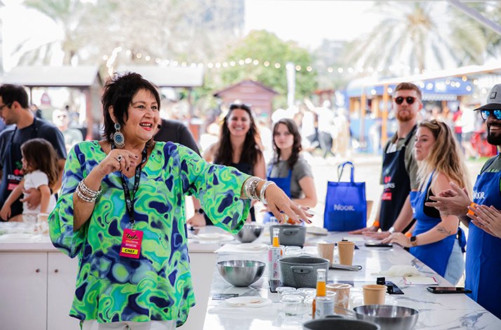 Chef leads an interactive cooking class outdoors with guests gathered around