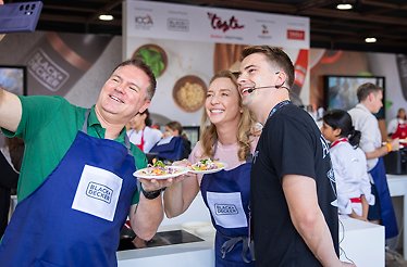Participants in aprons present colorful dishes at a cooking station during the event