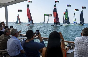 Guests enjoy front-row waterfront seating, watching SailGP yachts race by and capturing the action on their phones.