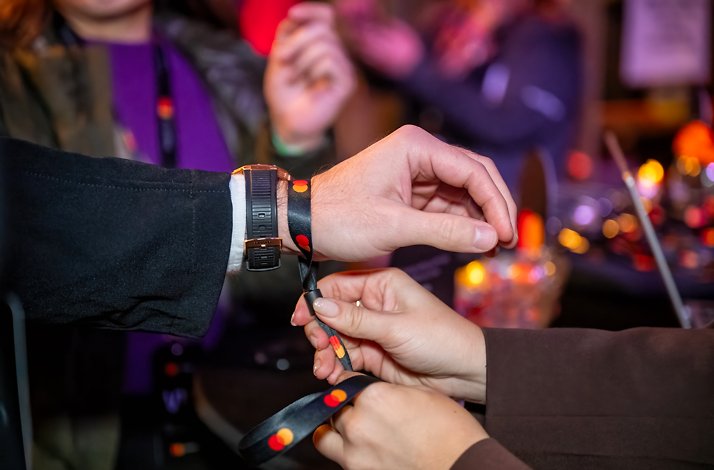 A person zipping up a Mastercard branded VIP wristband.