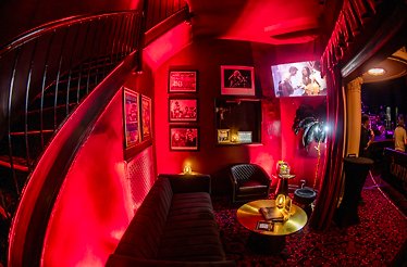 The private Stage Lounge at The Capitol Theatre, featuring red ambience lighting and curated rock 'n' roll photography.