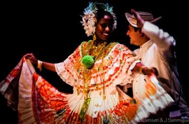 A man and woman in traditional attire perform a lively dance together, showcasing their cultural heritage.
