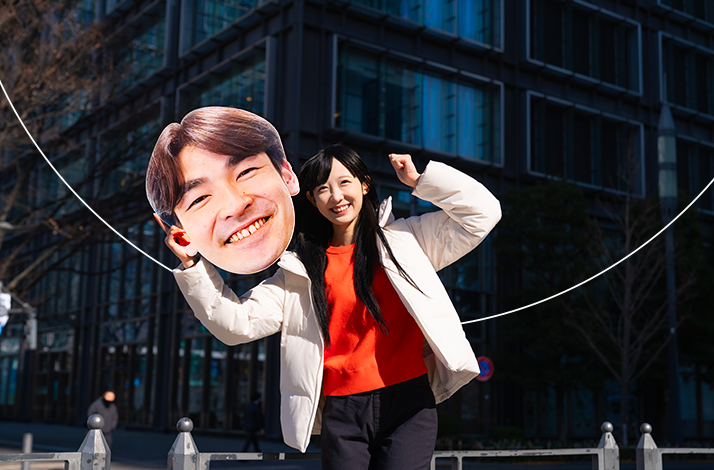 A fan holding a Mastercard in collaboration with Tokyo Marathon big head cut-out of a marathon runner.