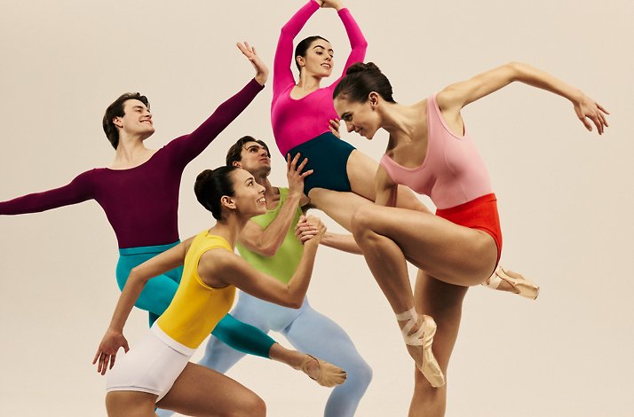 Group of ballet dancers in colorful leotards striking a dynamic pose.