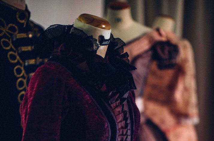 Mannequins dressed in ornate, vintage-style costumes in a dimly lit room.
