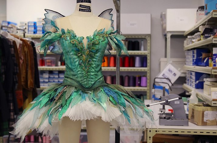 Mannequin wearing a detailed green fairy tutu in a costume workshop.