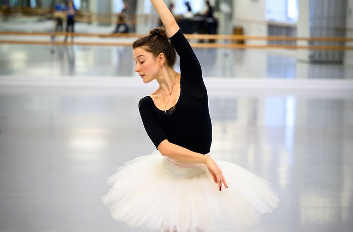 Ballerina in a white tutu posing gracefully in a dance studio.