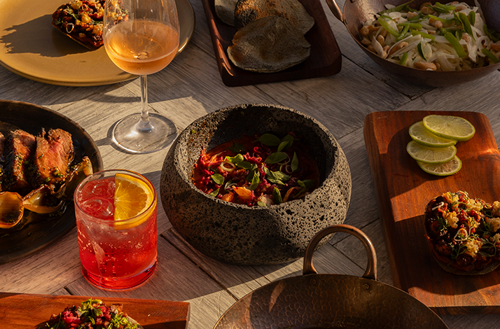 Arrangement of various dishes and beverages on a rustic wooden table at Hotel El Ganzo