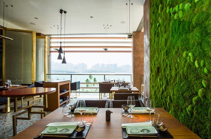The elegant japanese-themed furniture and seatings next to a stylish grass wall at 99 Sushi Bar Abu Dhabi.