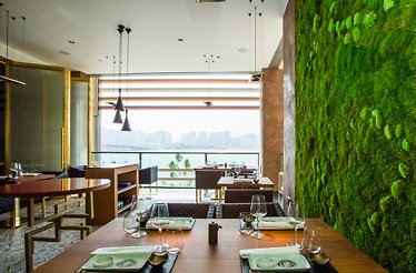 The elegant japanese-themed furniture and seatings next to a stylish grass wall at 99 Sushi Bar Abu Dhabi.