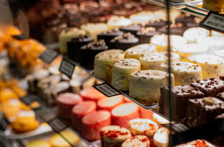 A display case filled with a variety of colorful pastries, cakes, and desserts