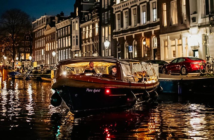 Front view of the elegant Pure Spirit on the shimmering canals of Amsterdam during the Light Festival.