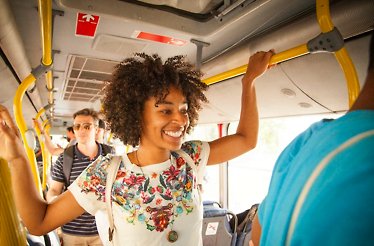 Passengers standing and holding yellow handrails inside a Ticketpro Bus in South Africa.