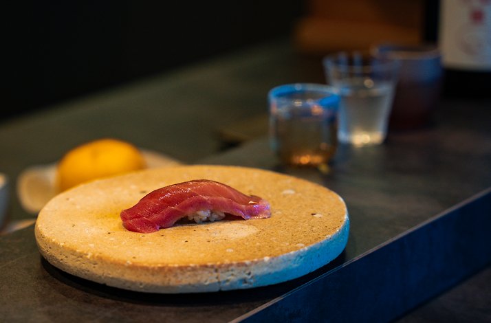 Tuna nigiri sushi on a round stone plate.