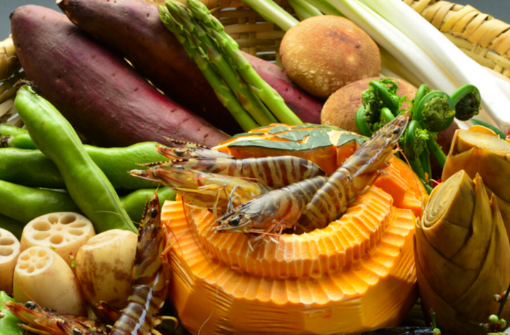 Beautifully presented Japanese multi-course meal, known as kaiseki, served on a long platter with a scenic koi pond in the background. 