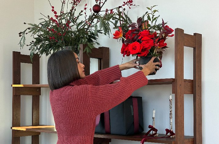 A woman placing pots of flowers on shelves.