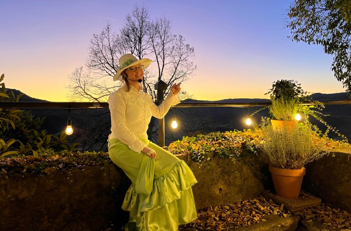 Costumed guide seated on a stone wall at sunset in Buzet, Istria.