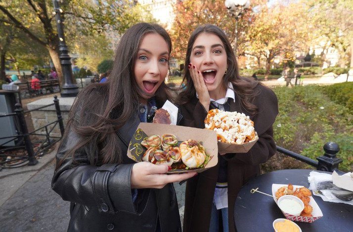 Sistersnacking sisters holding carton baskets with New York City snacks.
