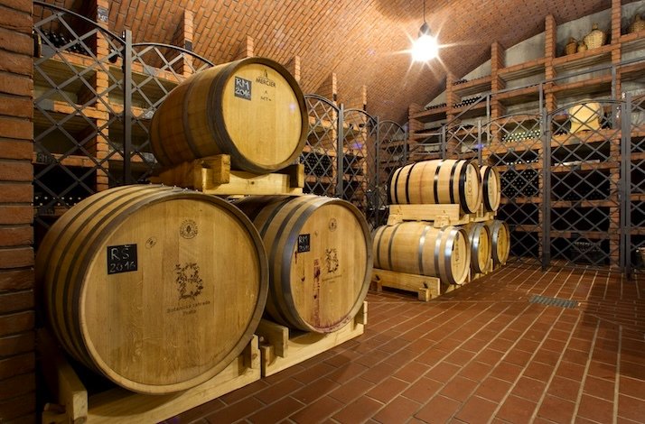 Wooden barrels filled with wine stored in the cellar at St. Claire’s Vineyard.