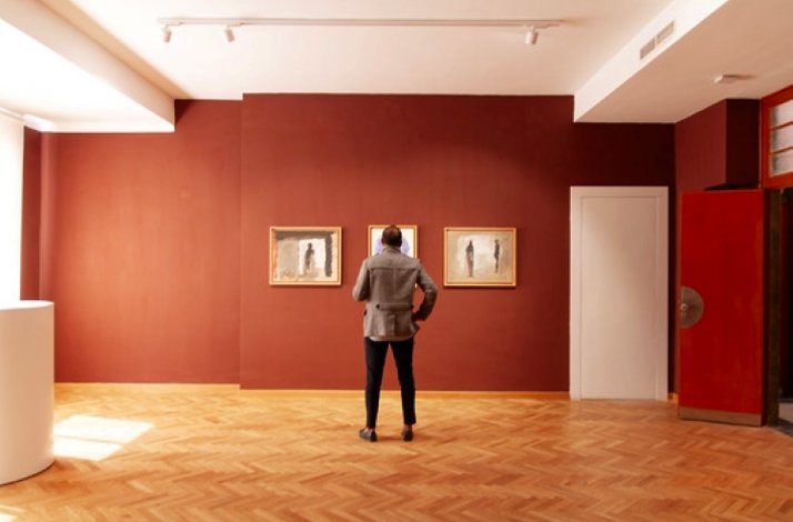 Person viewing paintings in an art gallery.