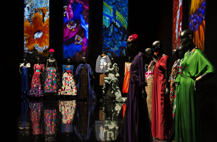 Art gallery exhibit with mannequins in colorful gowns.