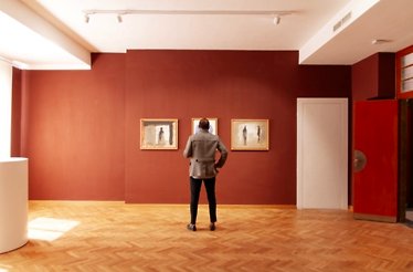 Person viewing paintings in an art gallery.