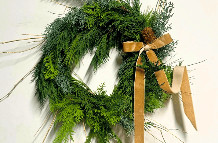 A natural Christmas wreath made of evergreen branches and a velvet ribbon.