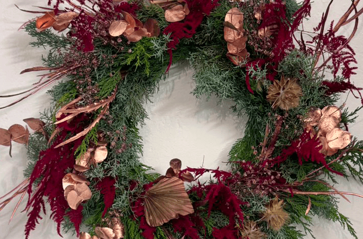 A Christmas wreath featuring a mix of evergreen pine needles and red foliage. 