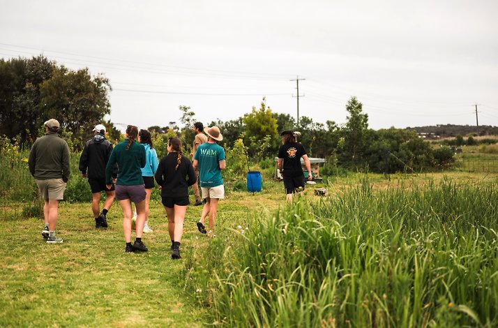 Group of people walking together through grassy outdoor trails.