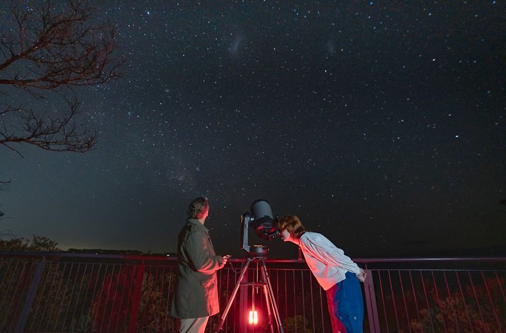 Two people stargazing with a telescope in the Blue Mountains at night.