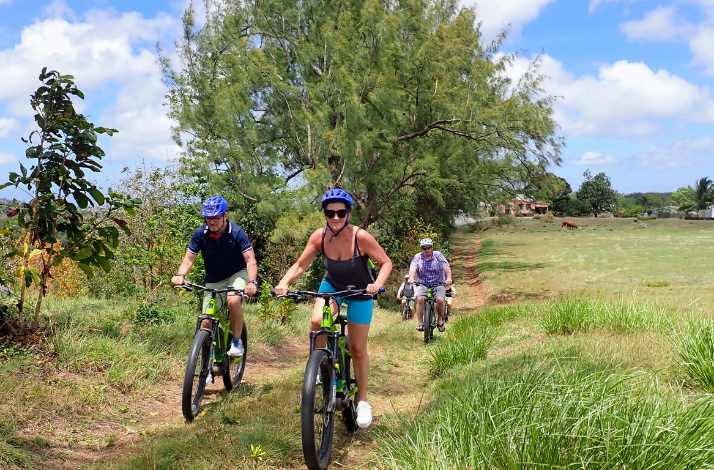 A group of cyclists enjoys a scenic mountain biking excursion on a dirt trail in Barbados