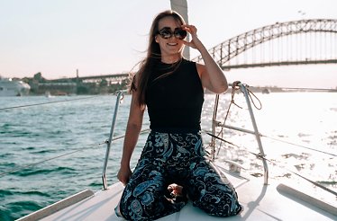 A woman wearing sunglasses posing for a golden-hour portrait on a private yacht.