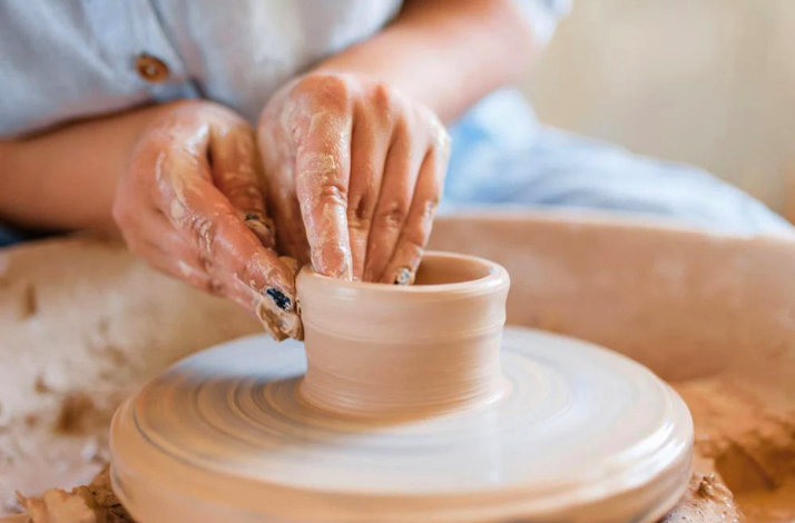 The art of pottery making with Jamaican artisans, specifically the technique known as wheel throwing.