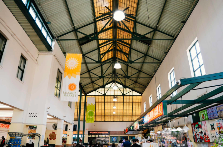 Interior of Jamaica Market, featuring high ceilings, banners, and food stalls.