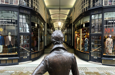 View from behind a statue overlooking shopping displays and storefronts on a London street featuring the portrait of local guide Tom