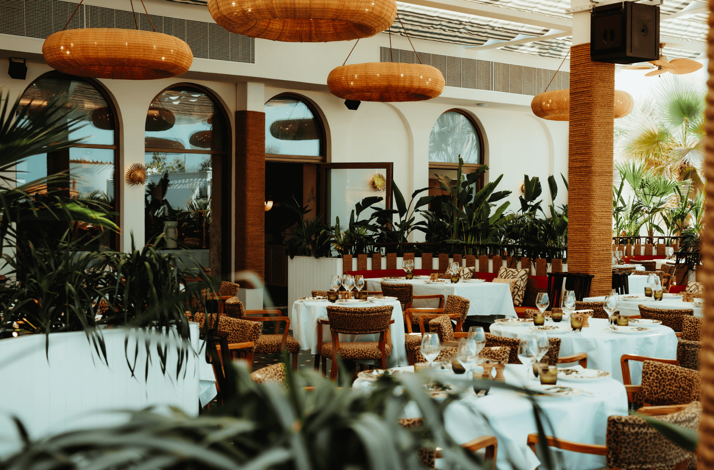 The elegant dining area at Restaurant African Queen Dubai, featuring greenery and Tiki style overhead lighting.