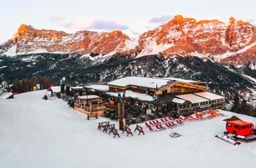 Aerial shot of Club Moritzino on Piz La Ila at sunset, dominated by its wooden lodge and its surrounding structures.