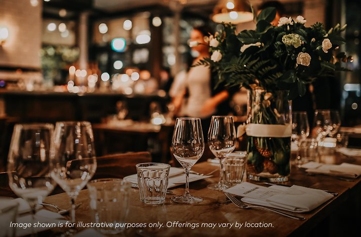 Promotional image of a table set with glasses and a plant ornament at a bar.