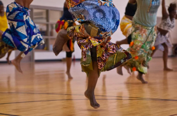  A diverse group of young people in vibrant clothing joyfully dancing together in a lively setting.