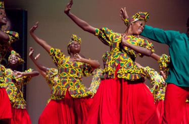  Dancers in vibrant African clothing perform energetically on stage, showcasing cultural traditions and artistry.