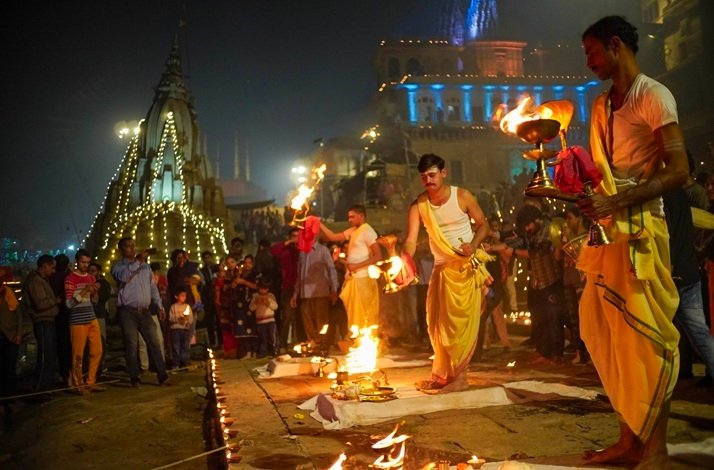A group of people lighting and placing candles on the ground, creating a warm, glowing atmosphere.
